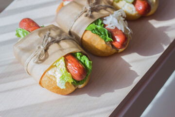 Homemade hot dogs on a light wooden background in eco-packaging.Fast food.Close up.Hard light.National hot dog day holiday.