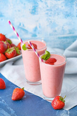 Glasses of tasty strawberry smoothie on color background