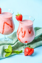 Glasses of tasty strawberry smoothie on color background