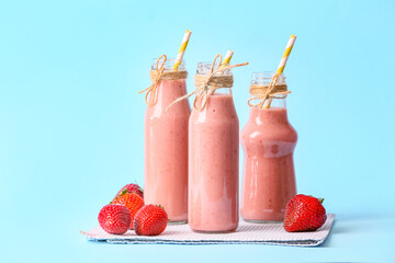 Bottles of tasty strawberry smoothie on color background