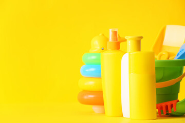 Sunscreen cream with beach sand toys on color background