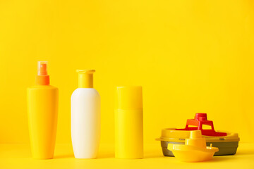 Sunscreen cream with beach sand toys on color background