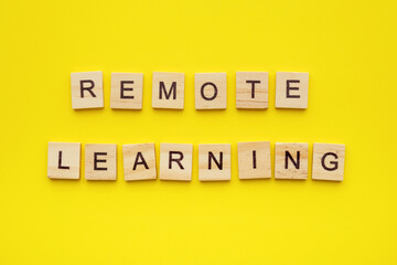 Wooden letter cubes on yellow background with phrase remote learning. possibility of continuing distance learning creative concept