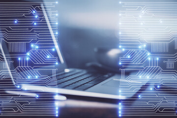 Computer on desktop in office with technology theme hologram. Double exposure. Tech concept.