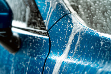 Blue car wash with white soap foam. Auto care business. Car cleaning and shining before waxing...
