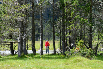 fly fisherman trout fishing with a hiking backpack and an orange jacket in the high mountains in summer
