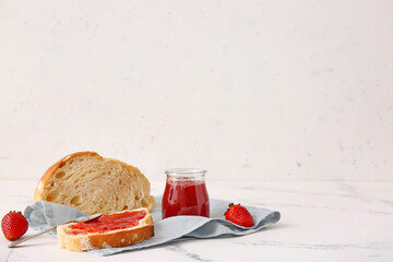 Tasty strawberry jam and bread on table