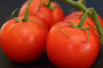 Juicy fresh tomatoes on black background close up