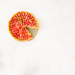 Fresh homemade strawberry shortcrust tart pie stuffed with custard vanilla cream . Sliced berries and mint leaf on the trendy white concrete background isolated. Free copy space. Top view.