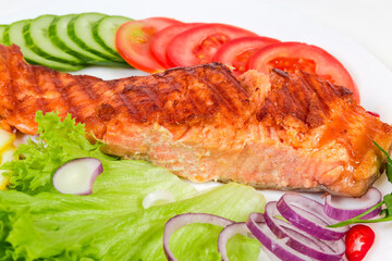 Piece of grilled trout fillet among the vegetables close-up