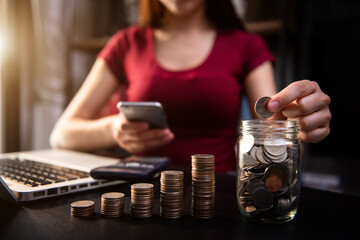 saving money with hand putting coins in jug glass and calculator to calculate budget concept finance and accounting 
