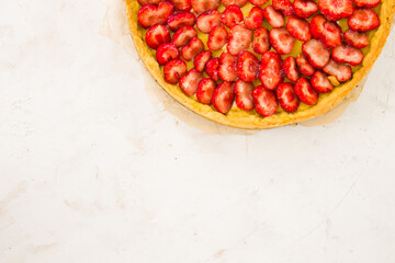 Fresh homemade strawberry shortcrust tart pie stuffed with custard vanilla cream . Sliced berries and mint leaf on the trendy white concrete background isolated. Free copy space. Top view.