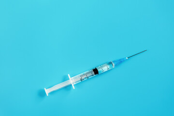 Medical syringe for injection on a blue background.