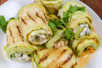 Zucchini rolls with different filling on dish, fragment close-up
