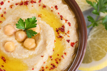 Chickpeas hummus with olive oil, paprika, parsley and lemon on a gray background.