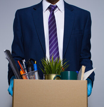Ofiice Worker In Gloves With His Cardboard Box Getting Fired From Job Concept Formal Wear On Gray Background