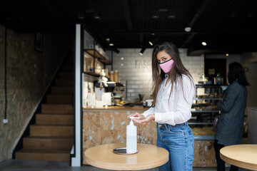 Woman using sanitizer gel cleans hands of coronavirus virus at cafe.