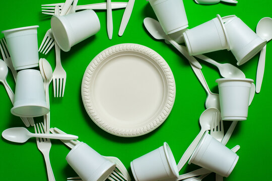 organic forks, spoons, plates and glasses of corn starch on a green background. isolate with place for text. biodegradable dishes. eco friendly. modern replacement for plastic.