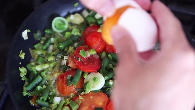 Cooking frittata with chicken eggs and fresh vegetables on pan in home kitchen.Delicious Italian breakfast meal preparation in close up.Natural ingredients frying for healthy lunch meal