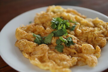 Angle view of Omelet top with coriander on wood table.(Thai style)