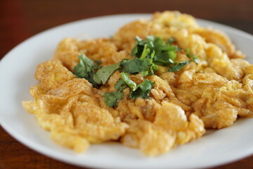 Close up side view of Omelet and top with coriander on wood table.(Thai style)