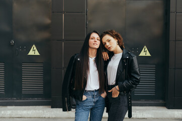 Portrait of two stylish girls in casual clothes posing at camera on black background, wearing...