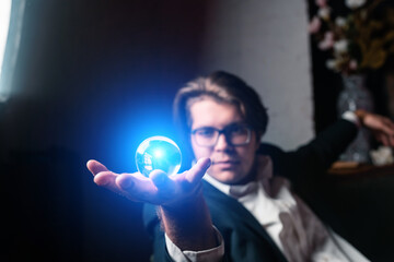 Young man holding a clear transparent crystal glass ball in their hand