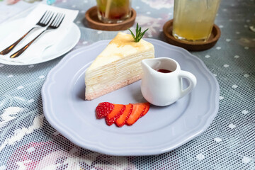 strawberry crepes cake with strawberry sauce on the table.