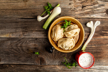 Uzbek prepared boiled Manti or manty dumplings in a traditional bowl on wooden table. banner menu recipe place for text
