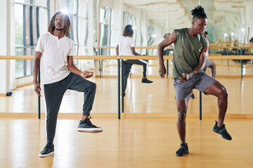 Fototapeta na wymiar Young Black man attending dance class and repeating movement after the teacher