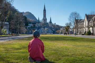 Obraz premium young boy with the cathedral-sanctuary of Lourdes (France)