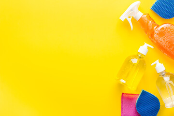 Household chemicals - detergents - bottles on yellow desk from above copy space