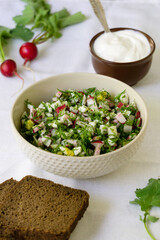Salad with radish, eggs and dill on a white fabric background