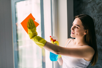 Young woman washing window. Housewife cleaning window at home. Housework