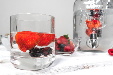 Glass of water flavored with berries. Red fruit flavoured water. Cocktail. Summer drink. Refreshing drink.Ingredients for preparing red fruits flavored water. Glass with refreshing liquid