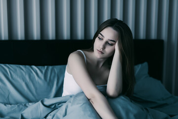 Young pretty woman suffering from depression sitting on bed