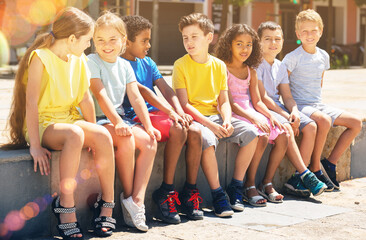 Positive children chatting together sitting at urban street