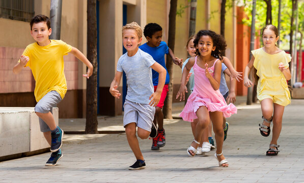 Cheerful active children are racing along the street