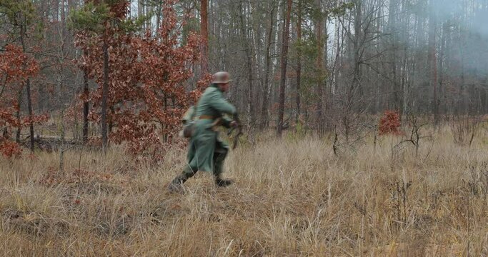 Historical Re-enactment. Re-enactor Dressed Like German Wehrmacht Infantry Soldier In World War II Running With sub-machine gun and open fire In Forest