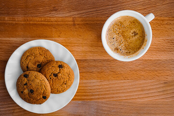 Oatmeal cookies on a plate on a table with a wooden texture and coffee