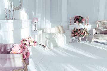 luxury clean bright white interior. a spacious room with sunlight and flowers in vases and royal chic furniture. 