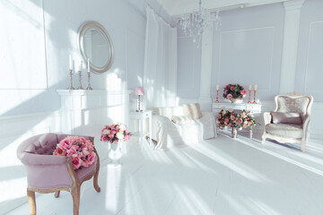 luxury clean bright white interior. a spacious room with sunlight and flowers in vases and royal chic furniture. 