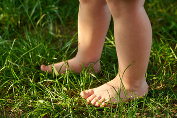 The feet of a small child on the grass, walking on bumps.