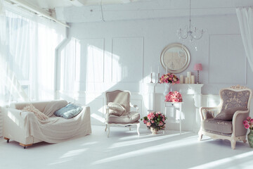luxury clean bright white interior. a spacious room with sunlight and flowers in vases and royal chic furniture. 