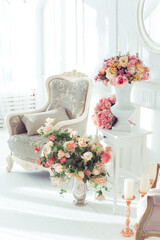 luxury clean bright white interior. a spacious room with sunlight and flowers in vases and royal chic furniture. 