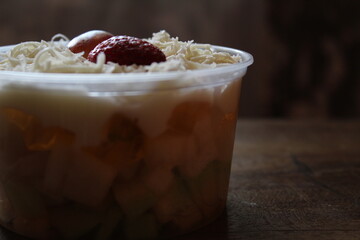 fruit salad from pineapple, oranges, grapes and coconut with marshmallow and vanilla yogurt close-up on a plate. horizontal