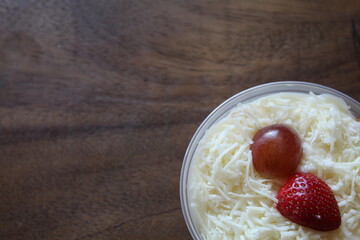 fruit salad from pineapple, oranges, grapes and coconut with marshmallow and vanilla yogurt close-up on a plate. horizontal