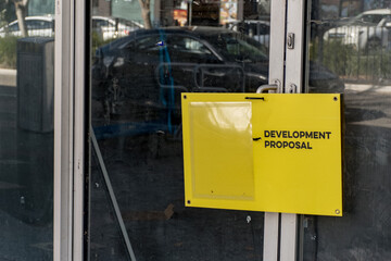 Development proposal yellow board on a dusty and dirty office building window in Sydney, NSW, Australia