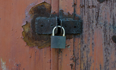 Padlock on the door. Iron door. Cracked paint.