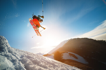 man skier in flight after jumping from a kicker in the spring against the backdrop of mountains and...